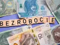 Litery układają się w słowo "BEZROBOCIE" na tle polskich banknotów. Zastanawiasz się, ile wynosi zasiłek dla bezrobotnych?