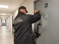 Strażnik więzienny przy drzwiach celi nr 23. Czy pobyt w zakładzie karnym wlicza się do emerytury? To pytanie nurtuje wielu.