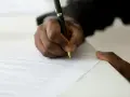 Dłoń podpisuje dokument, być może list motywacyjny do ZUS.