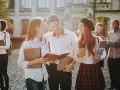 Studenci rozmawiający na kampusie, z książkami i notatkami w rękach. Wszyscy wyglądają na szczęśliwych, jakby właśnie skończyli zajęcia. To idealny obrazek dla osób, które chcą połączyć pracę z nauką, wybierając l4 a studia zaoczne.