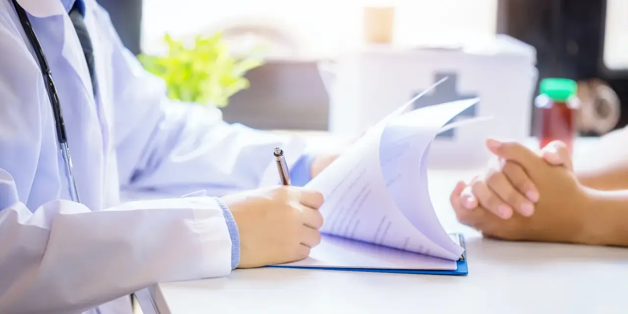 Lekarz analizuje dokumenty, rozważając powrót do pracy po zasiłku rehabilitacyjnym a dalsze L4.