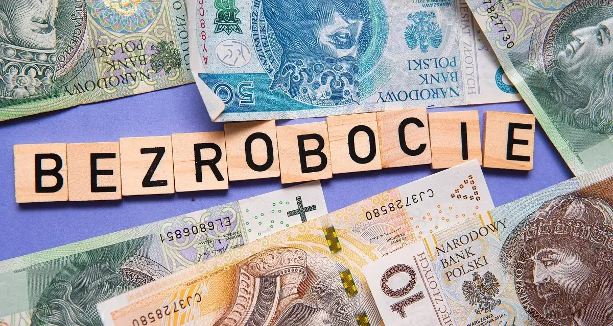 Litery układają się w słowo "BEZROBOCIE" na tle polskich banknotów. Zastanawiasz się, ile wynosi zasiłek dla bezrobotnych?