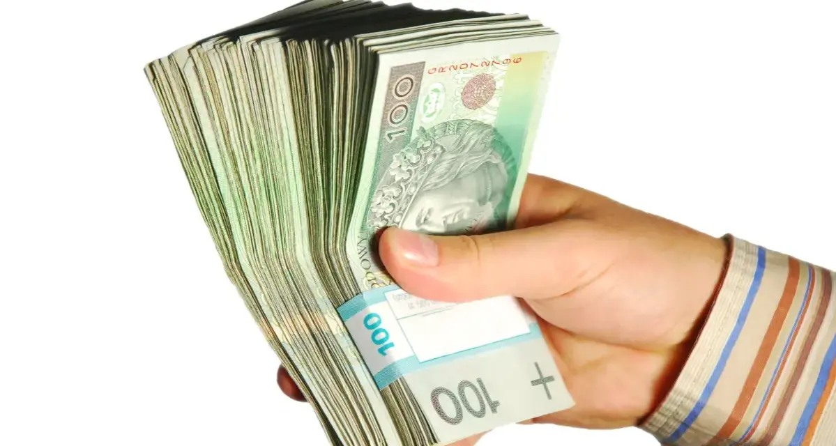 Dłoń trzyma plik banknotów 100 zł. Taka kwota z ubezpieczenia chorobowego przysługuje w wielu sytuacjach.