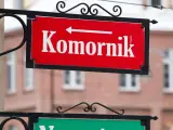 Czerwona tablica z napisem "Komornik" i strzałką w lewo. W tle budynek, może to być miejsce, gdzie zasiłek chorobowy jest zagrożony przez komornika.