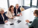 Biznesmeni dyskutują przy stole, czy od premii płaci się zus. Jedna z pań notuje.