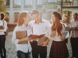 Studenci rozmawiający na kampusie, z książkami i notatkami w rękach. Wszyscy wyglądają na szczęśliwych, jakby właśnie skończyli zajęcia. To idealny obrazek dla osób, które chcą połączyć pracę z nauką, wybierając l4 a studia zaoczne.
