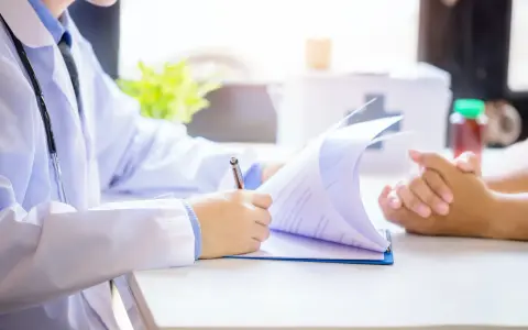 Lekarz analizuje dokumenty, rozważając powrót do pracy po zasiłku rehabilitacyjnym a dalsze L4.