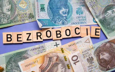 Litery układają się w słowo "BEZROBOCIE" na tle polskich banknotów. Zastanawiasz się, ile wynosi zasiłek dla bezrobotnych?