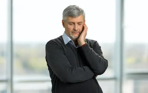 Pracujący rencista zamyślony, jakby rozważał zwolnienie lekarskie.