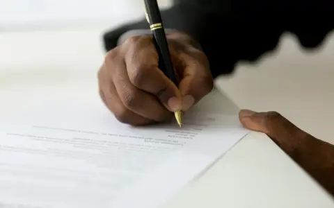 Dłoń podpisuje dokument, być może list motywacyjny do ZUS.