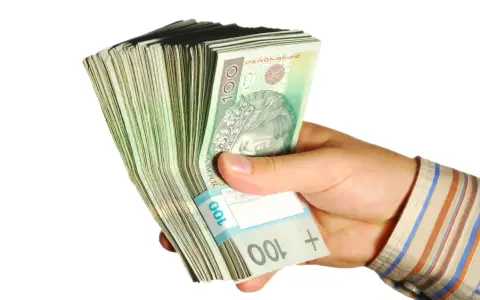 Dłoń trzyma plik banknotów 100 zł. Taka kwota z ubezpieczenia chorobowego przysługuje w wielu sytuacjach.