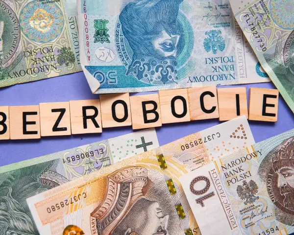 Litery układają się w słowo "BEZROBOCIE" na tle polskich banknotów. Zastanawiasz się, ile wynosi zasiłek dla bezrobotnych?