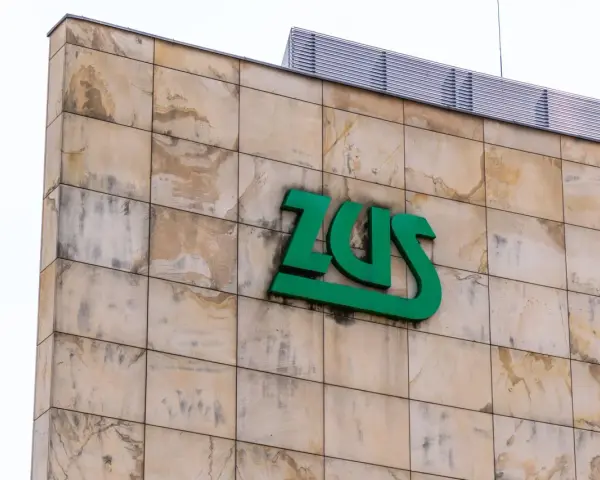 Zielone logo ZUS na beżowej, kamiennej elewacji. Czy chorobowe wlicza się do lat pracy? Zapytaj w ZUS.