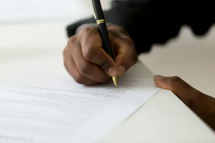 Dłoń podpisuje dokument, być może list motywacyjny do ZUS.