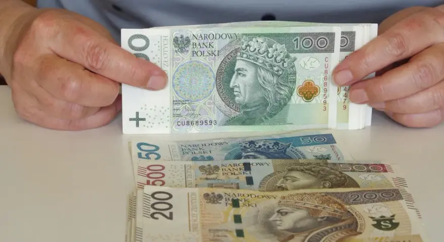 Ręce trzymają stos banknotów 100 zł. Pod spodem leżą banknoty 50, 500 i 200 zł. Pytanie: co po zasiłku rehabilitacyjnym?