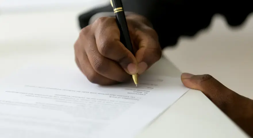 Dłoń podpisuje dokument, być może list motywacyjny do ZUS.