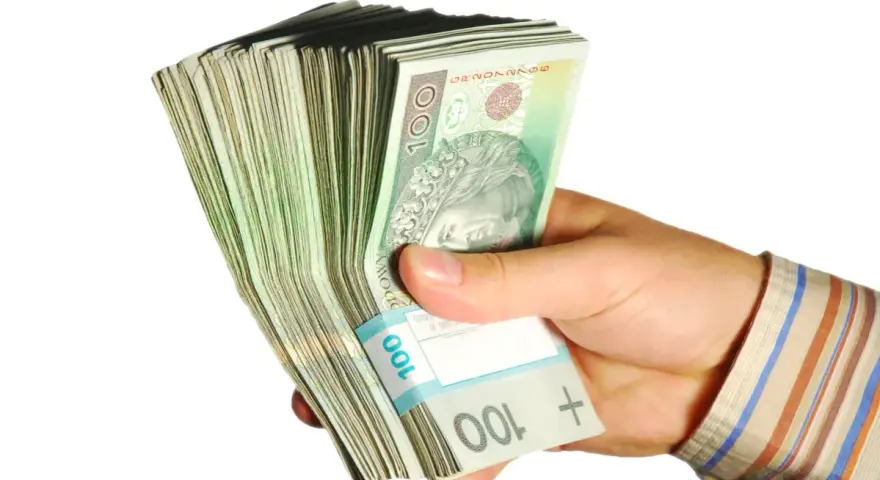 Dłoń trzyma plik banknotów 100 zł. Taka kwota z ubezpieczenia chorobowego przysługuje w wielu sytuacjach.