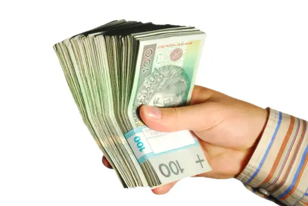 Dłoń trzyma plik banknotów 100 zł. Taka kwota z ubezpieczenia chorobowego przysługuje w wielu sytuacjach.