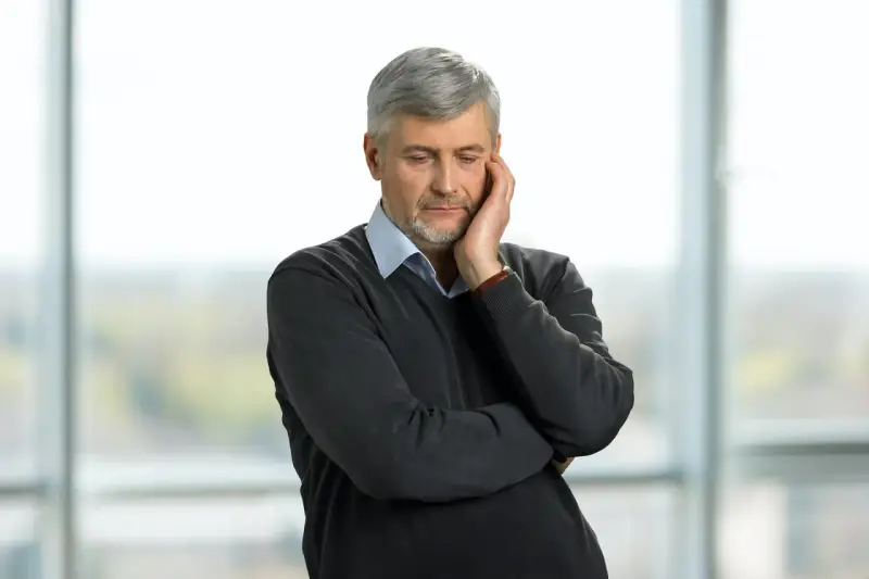 Pracujący rencista zamyślony, jakby rozważał zwolnienie lekarskie.